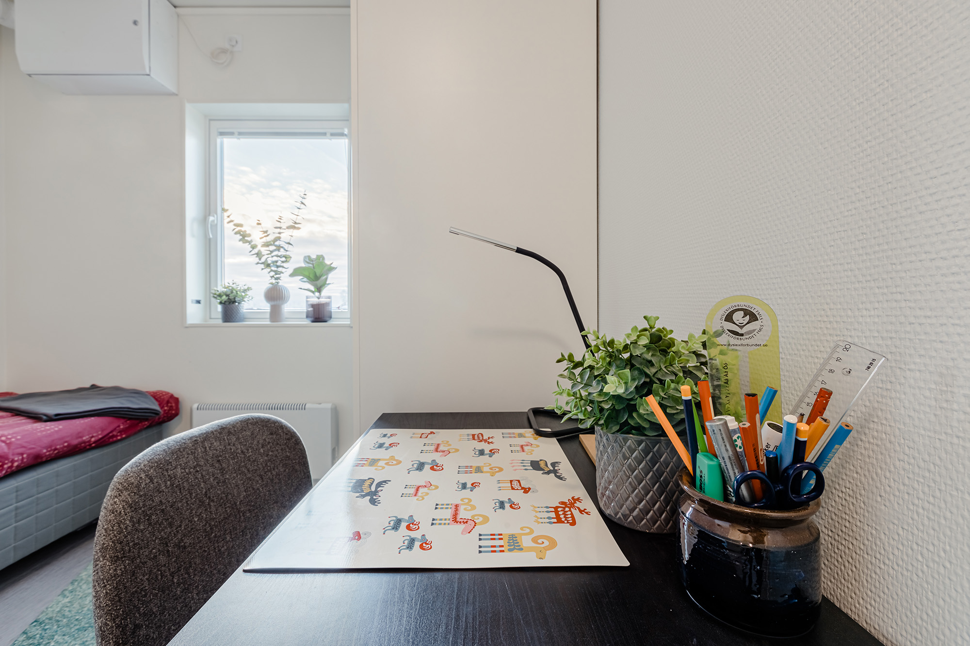 Studieplats i elevrum med skrivbord, förvaring och dagsljus.