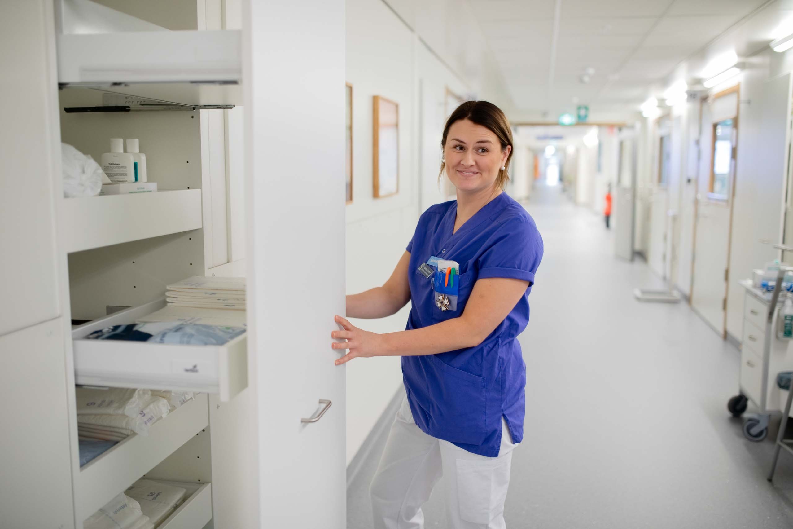 Vårdpersonal i korridor på Centralsjukhuset Karlstad i modulsjukhus från Expandia, hanterar medicinsk utrustning i förvaringsskåp
