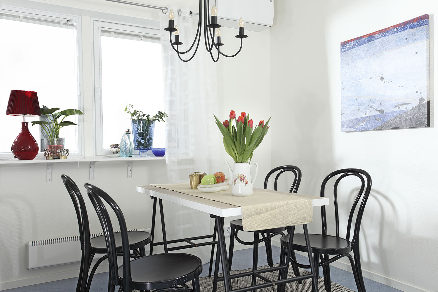 Matplats i boendemoduler från Expandia med bord och svarta stolar, tulpaner i vas, taklampa och fönster som ger ett ljust och hemtrevligt intryck.